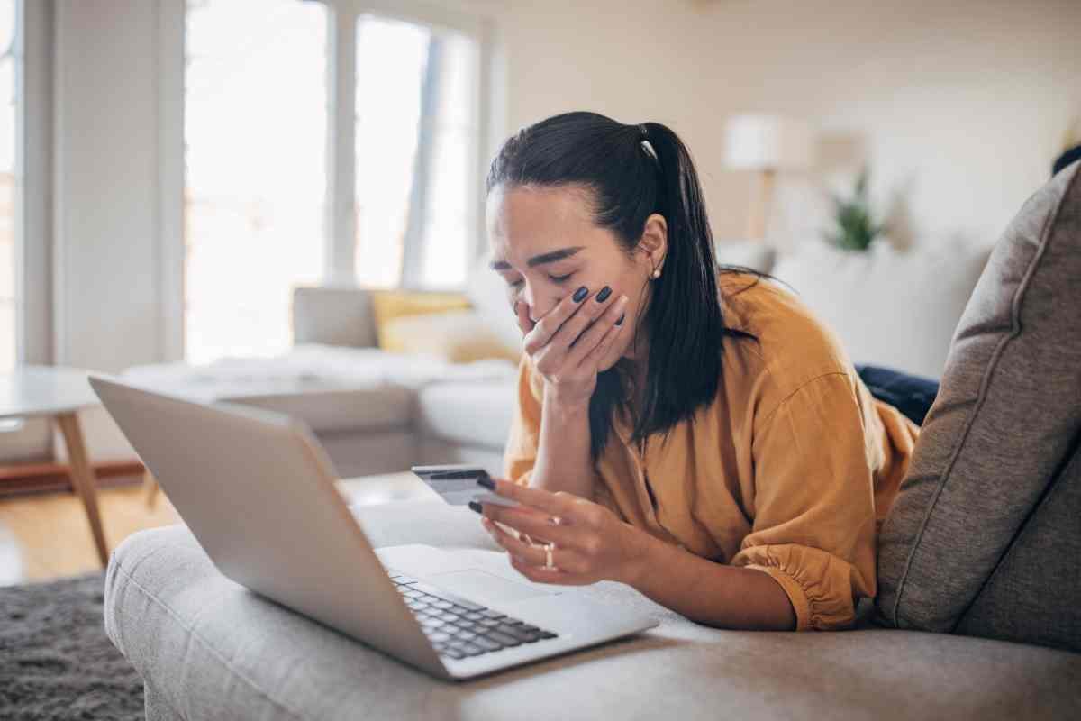 Donna spaventata con carta in mano al computer