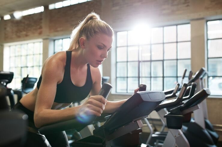 Donna bionda che guarda schermo della cyclette in palestra