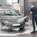 uomo con maglia nera che lava auto nera con idropulitrice