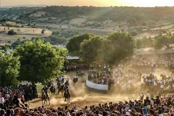 Persone che ammirano corsa equestre in uno spazio aperto di campagna 