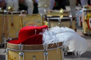 Tamburi, cappello rosso e piuma bianca