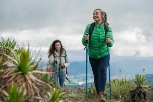 Due ragazze sorridenti con bastone che praticano trekking nella natura