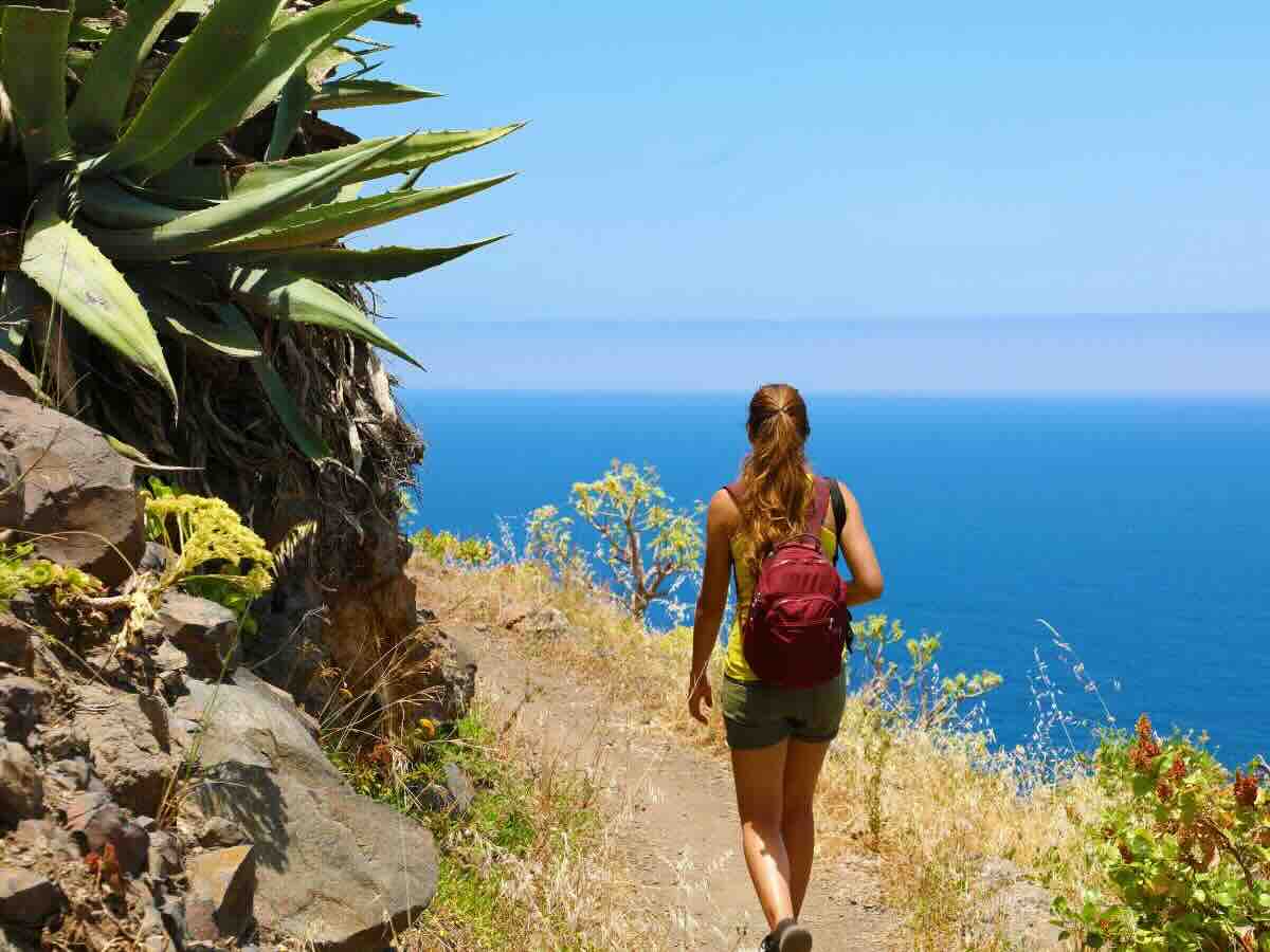 Ragazza in shorts e canotta che percorre un sentiero che affaccia sul mare