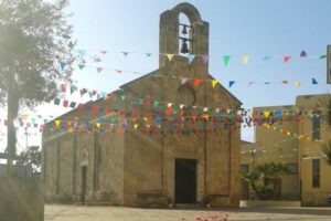 chiesa marroncina con campane e striscione colorato