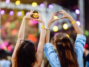 ragazze ad un concerto di spalle che formano un cuore con le mani