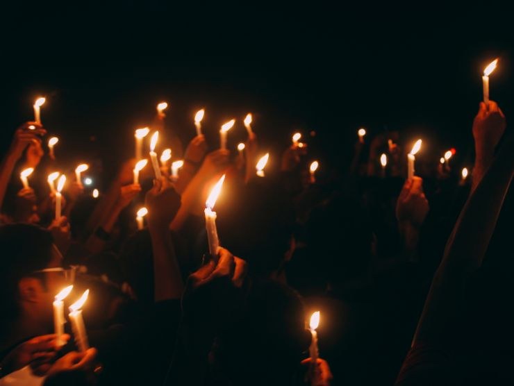 processione con uomini incappucciati e candele