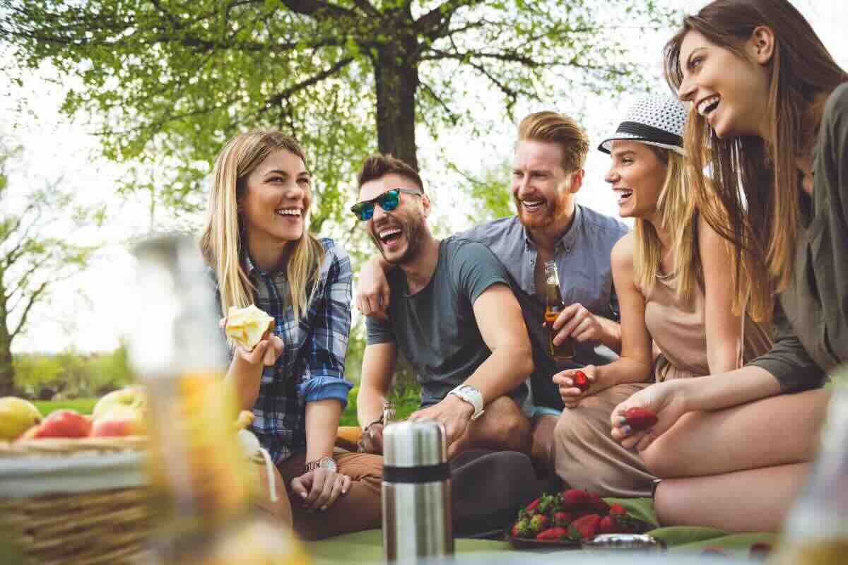 Gruppo di amici sorridenti che fa un picnic nella natura