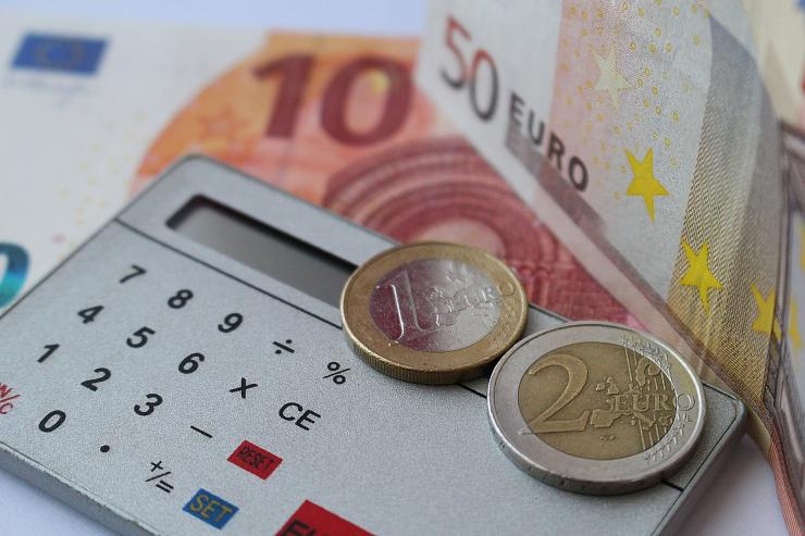 calcolatrice circondata da monete e banconote di euro