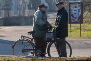 due anziani che parlano per strada e a fianco una bicicletta