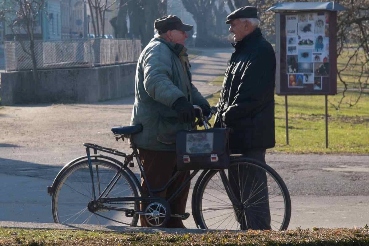 due anziani che parlano per strada e a fianco una bicicletta