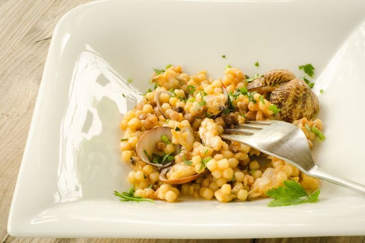 Piatto con forchetta e fregola, tipico formato di pasta sardo 