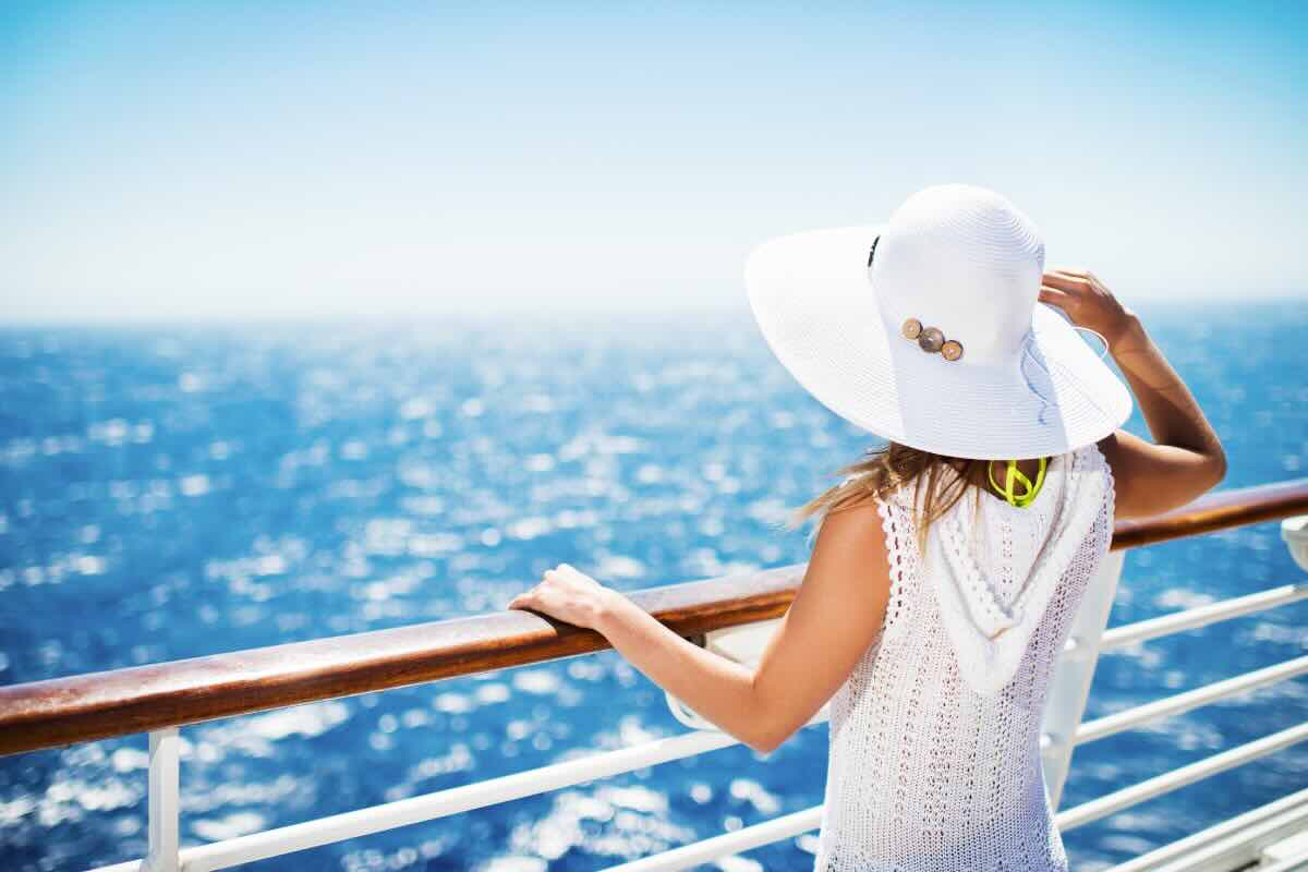 donna di spalle con cappello bianco che guarda il mare 