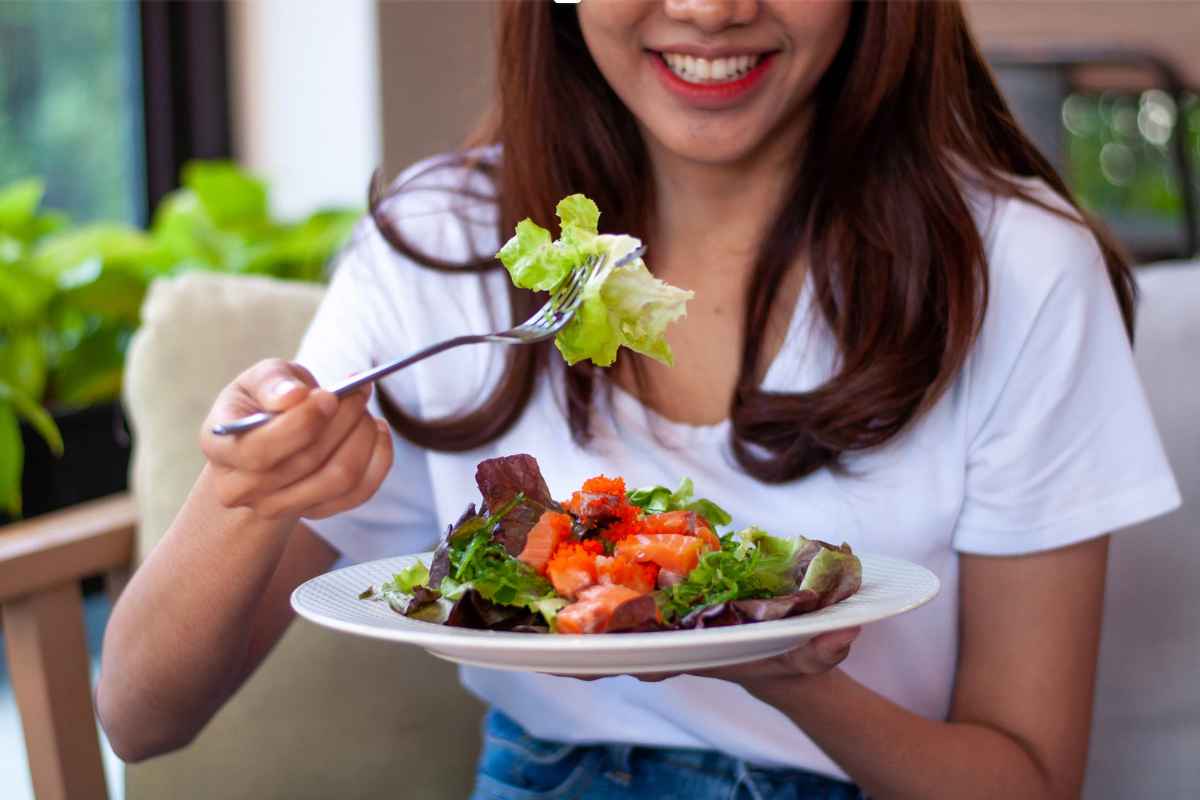 Donna con forchetta in mano, che mangia insalata