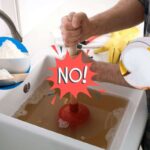 mano che cerca di sturare lavandino ostruito, con bicarbonato e acido citrico